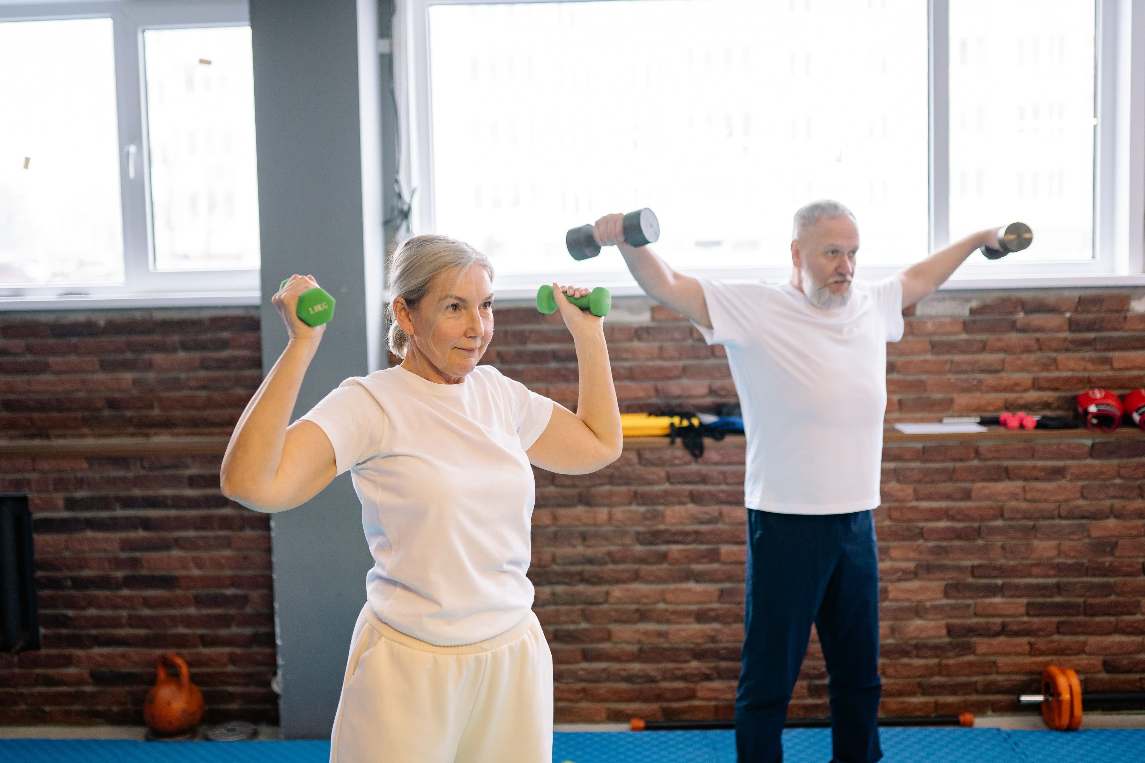 An older couple exercising together with dumbbells