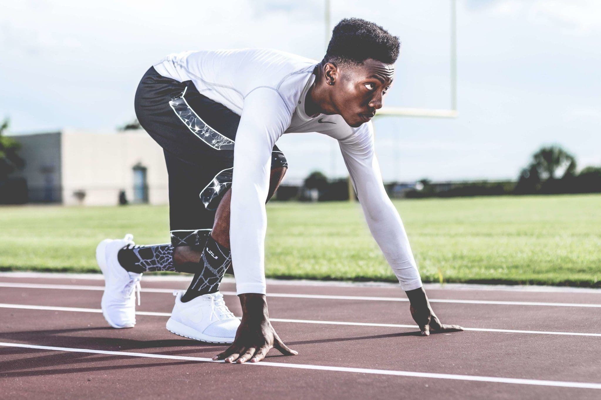 A man in a sprinter's starting stance on a track